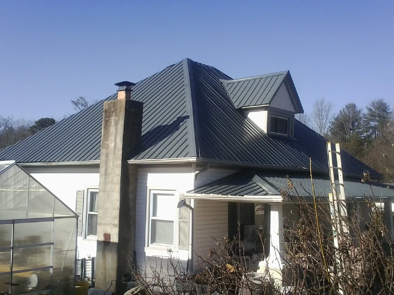 Dark blue standing seam metal roof on a white farmhouse with dormer — Slate & Tile Roof Repair by Roofing Brothers in Fargo