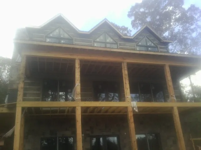 Dormers and porch framing on a large log home under construction — Roof Coating work by our crew in Fargo
